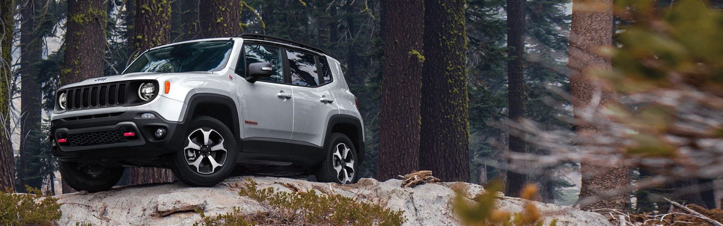 A red 2021 Jeep Renegade being driven through a tunnel with headlamps lit.